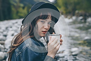 Unrecognizable Traveler Pouring Tea Or Coffee To Cup From Thermos On Waterfall Background. Tourism And Travel Concept