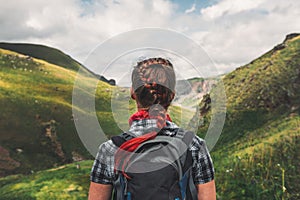 Unrecognizable traveler woman with backpack enjoying view of summer mountains, rear view