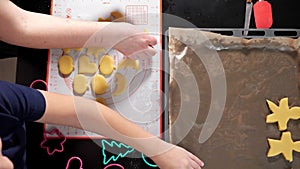 Unrecognizable woman and boy spread out dough of different shapes on a baking sheet slow motion