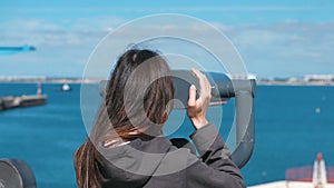 Unrecognizable woman brunette looks through binoculars at the sea.