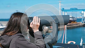Unrecognizable woman brunette looks through binoculars at the sea.