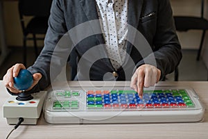 An unrecognizable woman with cerebral palsy is typing on the keyboard. A girl with disabilities works on a specially