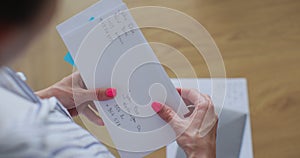 Unrecognizable woman checking mail holding papers documents. Caucasian female checking stack of letters at home.