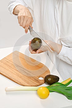 Unrecognizable woman cutting fresh avocado into halves