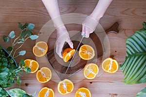 Unrecognizable woman cutting oranges in a kitchen full of plants.