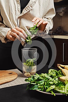 Unrecognizable woman drops spinach into blender