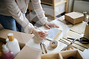 Unrecognizable woman dropshipper working at home, using tablet. Coronavirus concept.