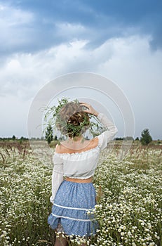 Unrecognizable woman in a field of wild white daisies in a picturesque valley