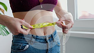 unrecognizable woman girl measuring her waist circumference with a tape measure