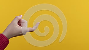 Unrecognizable woman giving beckoning finger sign. Close-up hand studio on yellow background. Flirt, temptation concept