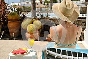 Unrecognizable woman in hat sitting on lounger