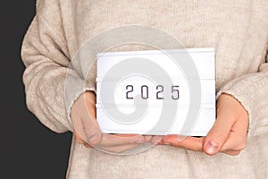 Unrecognizable woman hold in hands lightbox with 2025 numbers.