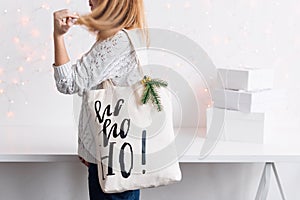 Unrecognizable woman holding Christmas gift in cloth bag. Happy winter holidays. Presents for Christmastime celebration..