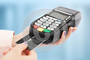 Unrecognizable woman holds swiping machine and credit card, pays for purchase, uses bank terminal in shop, isolated over blue back