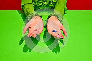 Unrecognizable woman holds two pills, red and blue tablets. Vitamins of beauty and health against sickness and ugliness.