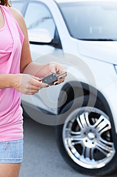 Unrecognizable woman with ignition key standing near new car