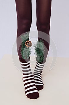 Unrecognizable woman legs wearing brown stripped socks and leggins. Holiday winter seasons. Home comfort wear concept