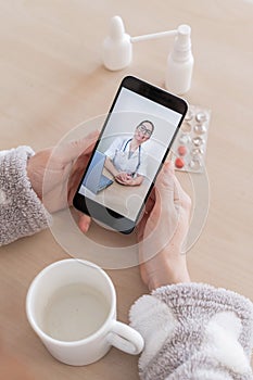 Unrecognizable woman on online consultation with a doctor on a cell phone. The girl is sick and talks to the attending