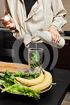 Unrecognizable woman pouring milk into blender