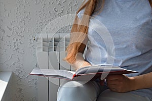 Unrecognizable woman reading book in bright room