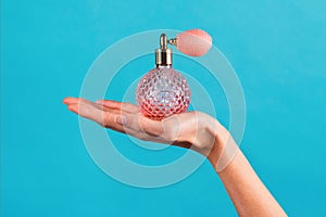Unrecognizable woman showing transparent perfume bottle in hand