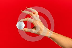 Unrecognizable woman showing white golf ball with fingers in light