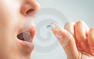 Unrecognizable woman taking a white round pill.