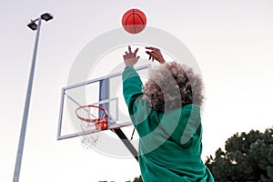 Unrecognizable woman throwing a ball into a basket