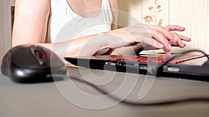 Unrecognizable woman using a mouse and typing something on laptop keyboard, shallow focus