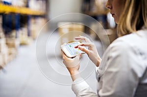 Woman warehouse worker or supervisor with smartphone.