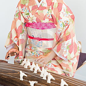 Unrecognizable woman wearing a kimono playing a koto, a traditional japanese string instrument