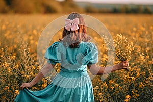 Unrecognizable woman in yellow canola flowers field.Lady in retro dress. Harvest