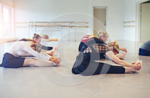 Unrecognizable women bending on floor in ballet class photo