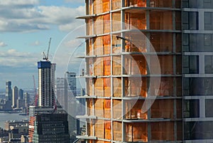 Unrecognizable worker kneeling while working on a skyscraper under construction.