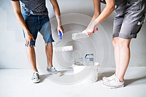 Unrecognizable young couple painting walls in their new house.