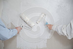 Unrecognizable young couple painting walls in their new house in construction.