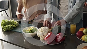 Unrecognizable young couple`s hands cooking together a healty meal. Plenty of various colorful vegetables on the kitchen