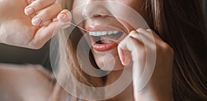 Unrecognizable young girl cleaning teeth with dental floss, close up
