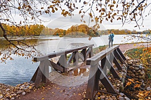 Unrecognizable young girl, view from the back, makes a photo of beautiful autumn landscapes on a smartphone, autumn walk