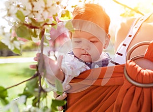 Unrecognizable young mother with her infant baby in sling