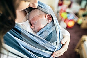 Unrecognizable young mother with her son in sling