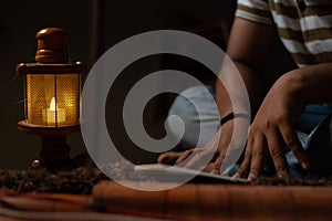 unrecognizable Young student busy reading during night under oil lamp or lantern due to power loss and Poverty - concpet