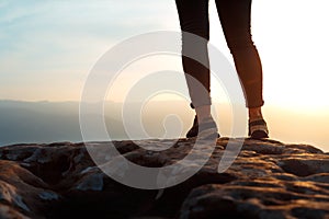 Unrecognizable young success woman hiker legs on mountain peak rock, rear view.  Concept achieving goal, beginning of the path,