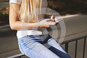 Unrecognizable young woman using smartphone mobile outside on city street