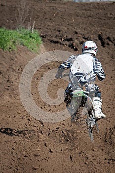 Unrecognized athlete riding a sports motorbike on a motocross racing event. Competitive sport