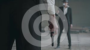 Unrecognized brutal man in formal suit stand across other man with gun in hand and smoking. Criminal grouping. Abandoned