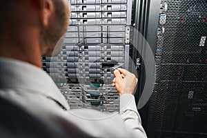Unrecognized European maintenance administrator examining supercomputer in serber room