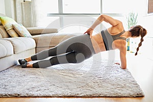 Unrecognized fit woman doing a lateral plank workout at home photo