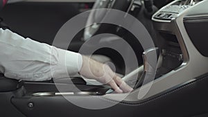 Unrecognized man sitting in the vehicle and inspects newly purchased auto from the car dealership. Car showroom