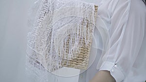 Unrecognized mature woman holding wicker basket while hanging white clothes on a clothesline outdoors. Washday